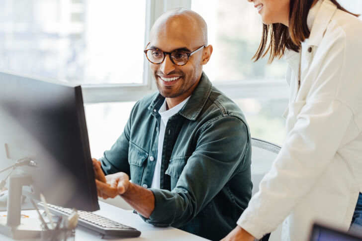 Man in glasses smiling while talking to female colleague