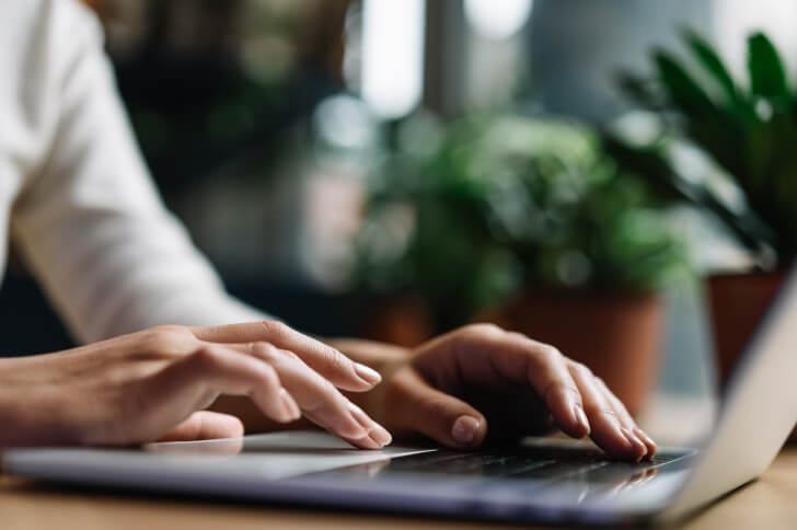 Two hands on a laptop keyboard using the mouse pad